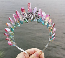 Front view of a bright rainbow crystal point crown with a silver-tone triple moon emblem and wire-wrapped band.