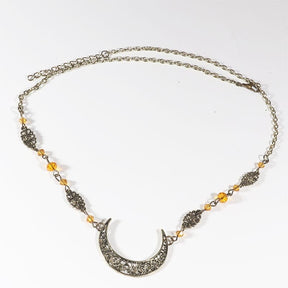 Bronze-tone crescent headdress with small amber-coloured faceted beads and patterned links, arranged in an oval on a pale background with the clasp and chain visible.