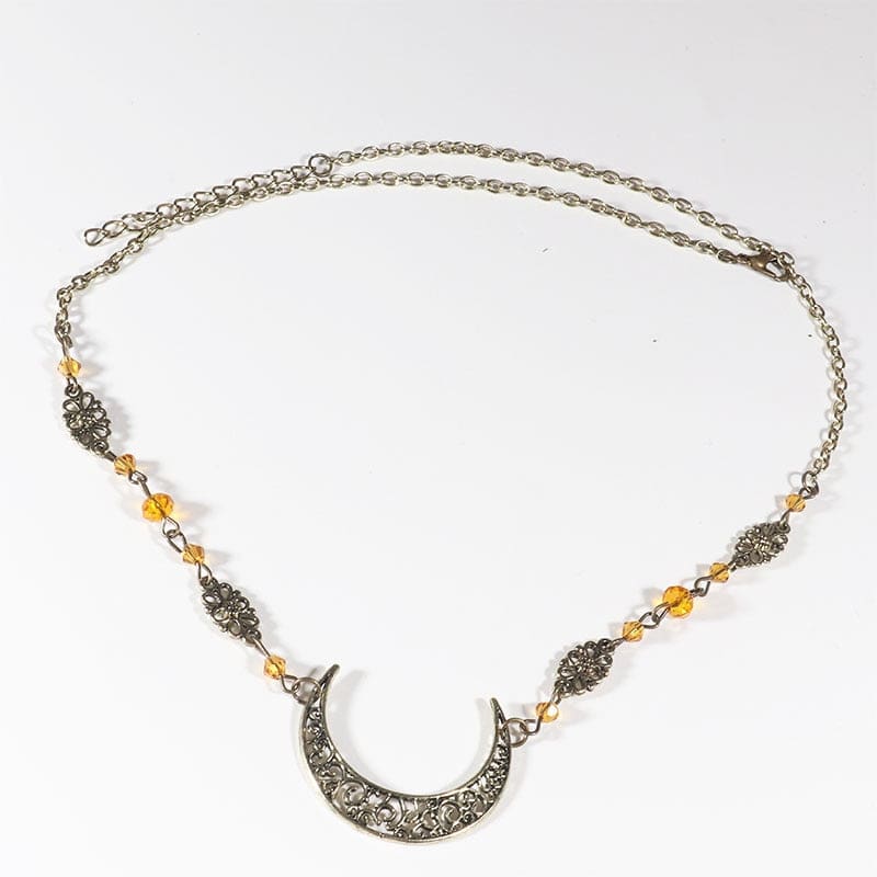 Bronze-tone crescent headdress with small amber-coloured faceted beads and patterned links, arranged in an oval on a pale background with the clasp and chain visible.