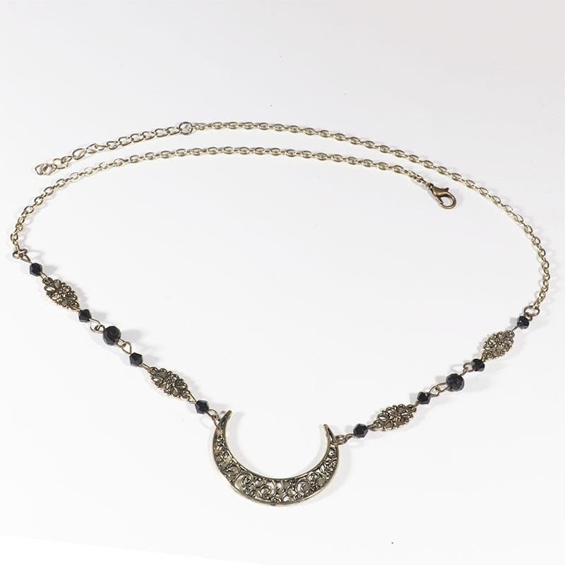 Bronze-tone crescent headdress with small black faceted beads, ornamental links and an extension chain, arranged in an oval on a pale background with the clasp and chain visible.