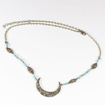 Bronze-tone crescent chain headdress with small pale blue faceted beads, arranged in an oval on a pale background with the clasp and chain visible.