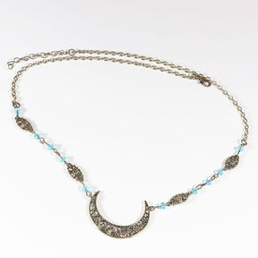 Bronze-tone crescent chain headdress with small pale blue faceted beads, arranged in an oval on a pale background with the clasp and chain visible.