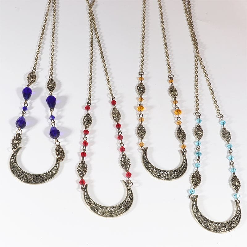 Four bronze-tone crescent headdresses hang side by side, comparing purple teardrop beads with smaller red, amber and pale blue beads.