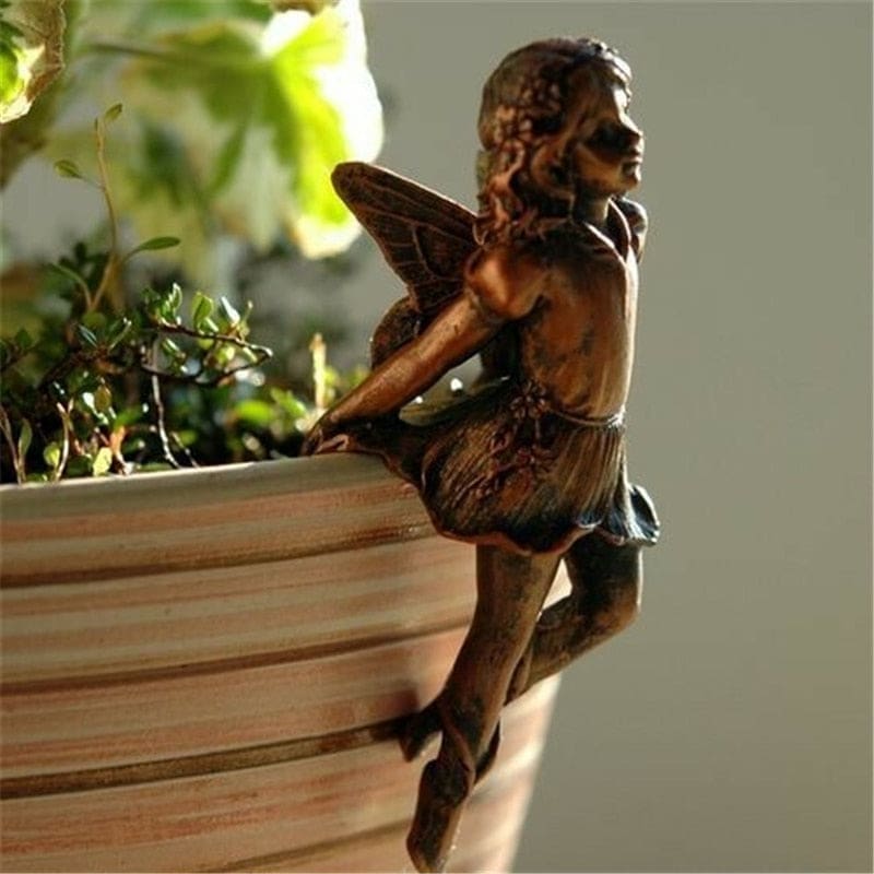 Closer profile of the seated bronze-tone fairy on a planter rim, showing the wing pattern and sculpted hair.
