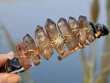 Brown crystal point tiara with a gold-tone sunburst motif and warm wire details between the upright points.