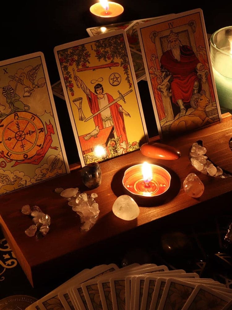 Brown moon phase card stand in warm candlelight, with three upright tarot cards, small crystals and a lit tealight in the centre recess.