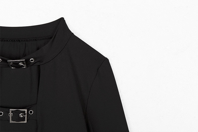 Detail view of the black crop top showing the buckled neck opening, shoulder seam and upper chest strap.