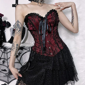 Burgundy strapless corset top with black floral lace with a view of the fitted waist and pointed hem.