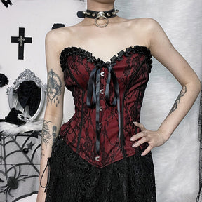 Burgundy strapless corset top with black floral lace shown from the front with a hand at the hip.