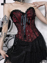 Burgundy strapless corset top with black floral lace worn from the front with hands near the waist.