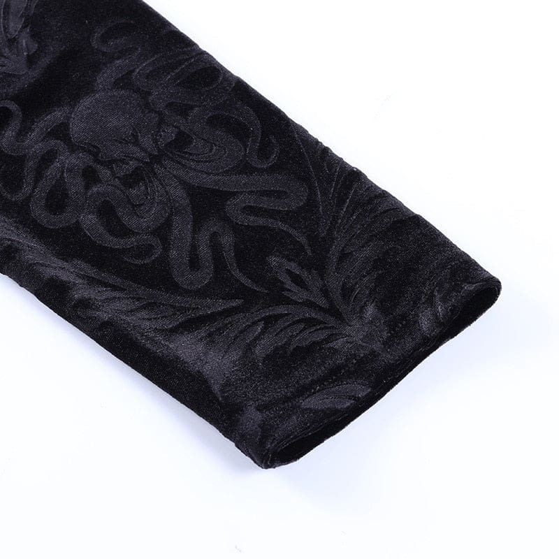 Black velvet trouser cuff viewed at an angle, with curled botanical motifs and a narrow stitched edge.