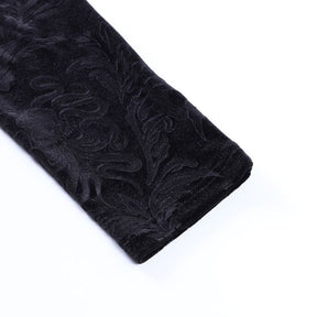 Close-up of a black trouser cuff, showing the serpentine and leaf pattern in the velvet and the stitched hem.