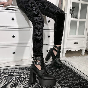 Close seated view of the patterned velvet trouser legs, with the botanical shapes catching the light above platform heels.
