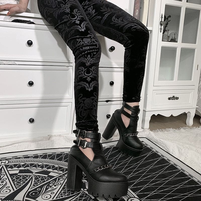 Close seated view of the patterned velvet trouser legs, with the botanical shapes catching the light above platform heels.
