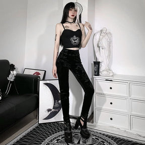 Black patterned velvet pants shown standing beside a white dresser, with the long narrow legs visible above black heels.