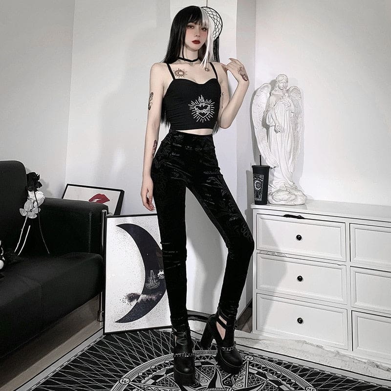 Black patterned velvet pants shown standing beside a white dresser, with the long narrow legs visible above black heels.