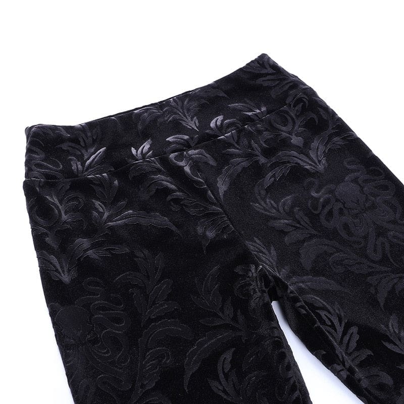 Flat detail of the black patterned velvet pants at the front waistband and upper legs.
