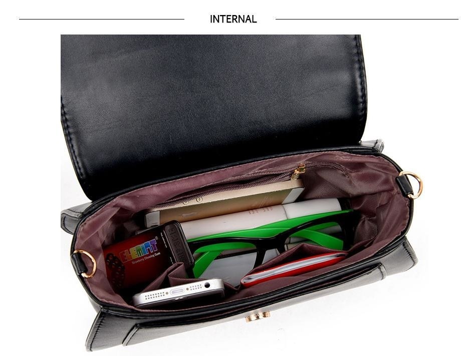 Open black cat-ear purse viewed from above, showing its lining, inner zip pocket and several small objects used to demonstrate the space.