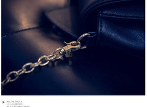 Close view of the gold-tone chain and detachable clip where the shoulder strap connects to the black cat-ear bag.