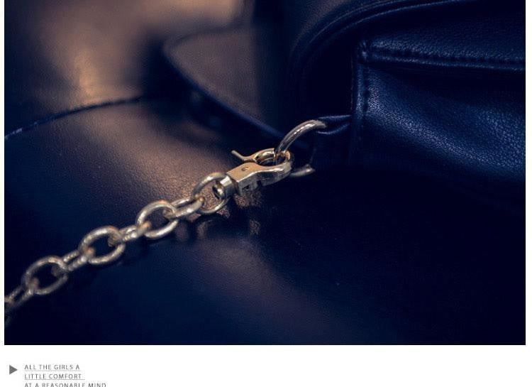 Close view of the gold-tone chain and detachable clip where the shoulder strap connects to the black cat-ear bag.
