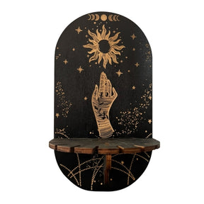 Black wooden display shelf with a gold-tone illustrated hand below a sun and moon phases, with printed chain-like lines beneath the ledge.