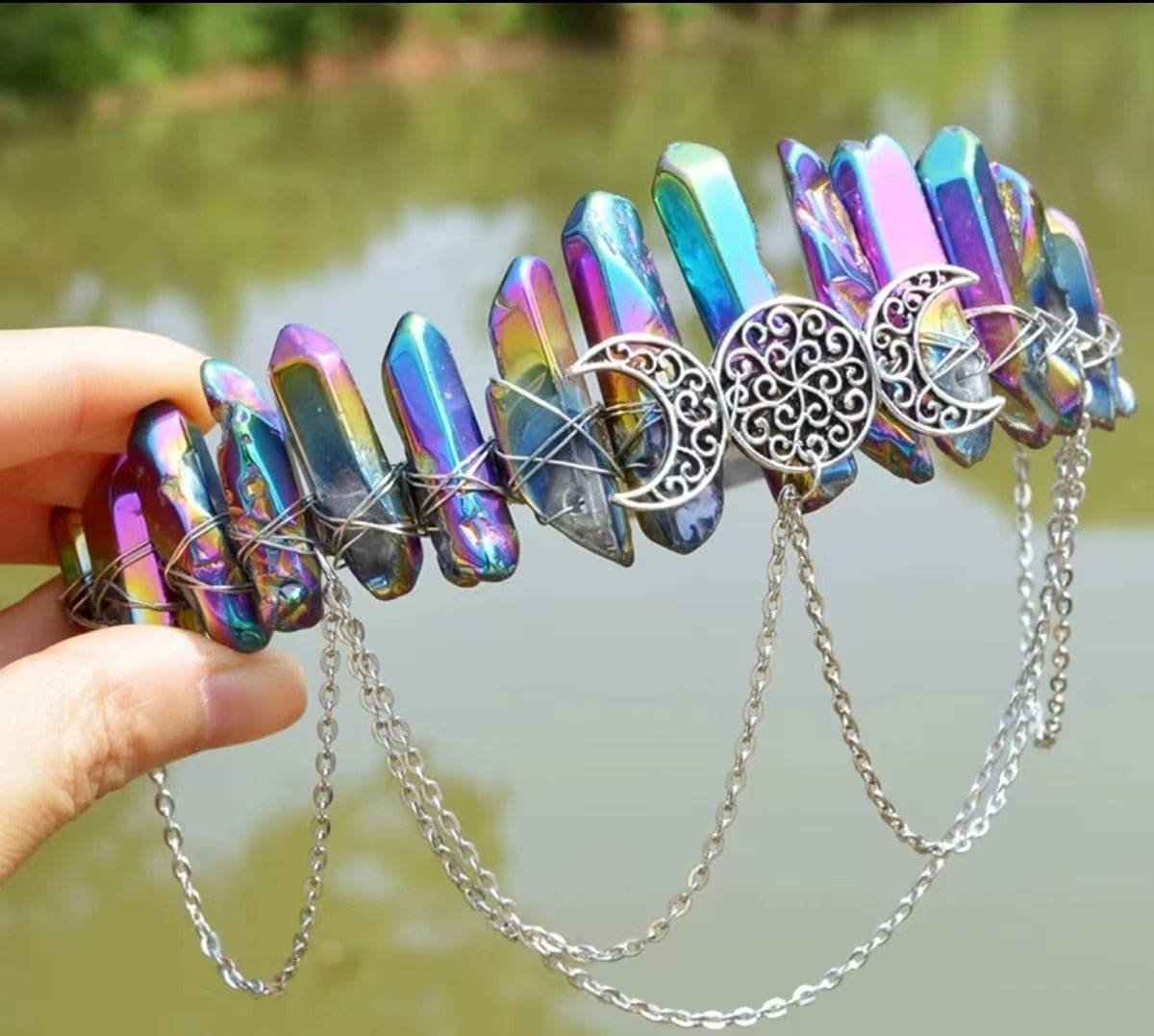Metallic rainbow crystal crown showing purple, blue and gold reflections around a triple-moon emblem.