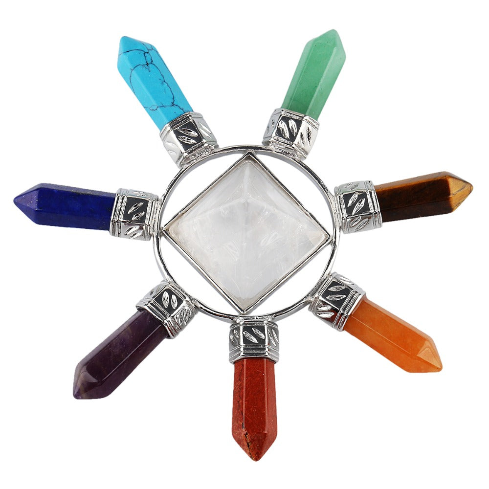 Overhead view of seven colourful crystal points arranged around a pale central quartz pyramid in silver-tone settings.