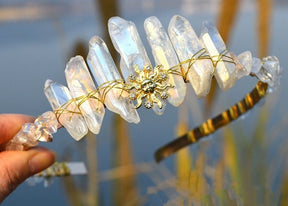 Front view of the clear crystal sun face tiara, showing pale irregular points around the golden facial motif.