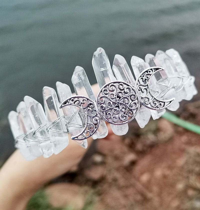Silver-tone triple moon emblem framed by clear crystal points, shown in a three-quarter view of the crown.
