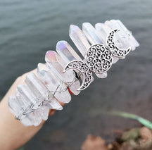 Angled view of a clear crystal point crown with a silver-tone triple moon emblem and wire-wrapped band.