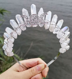 Front view of a clear crystal point crown with a silver-tone triple moon emblem and wire-wrapped band.