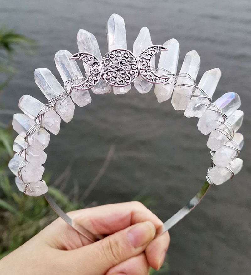Front view of a clear crystal point crown with a silver-tone triple moon emblem and wire-wrapped band.