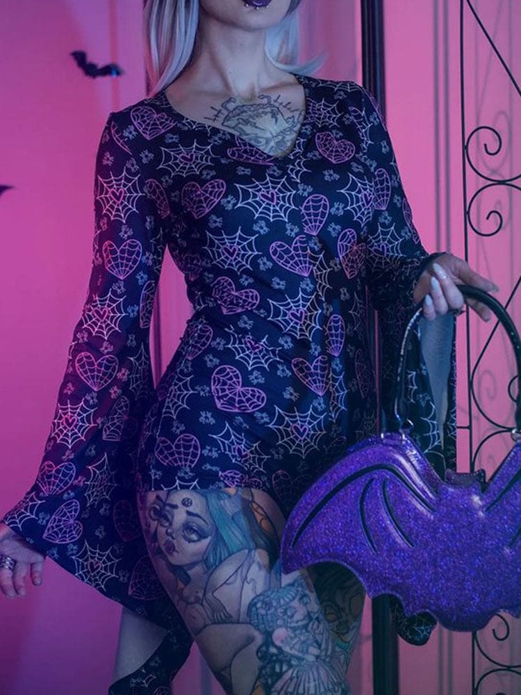 Black Cobweb Queen bodysuit covered in web-filled hearts, cobwebs and tiny bats, with a V-neck and long draped bell sleeves. Shown under purple and blue lighting beside a bat-shaped bag.