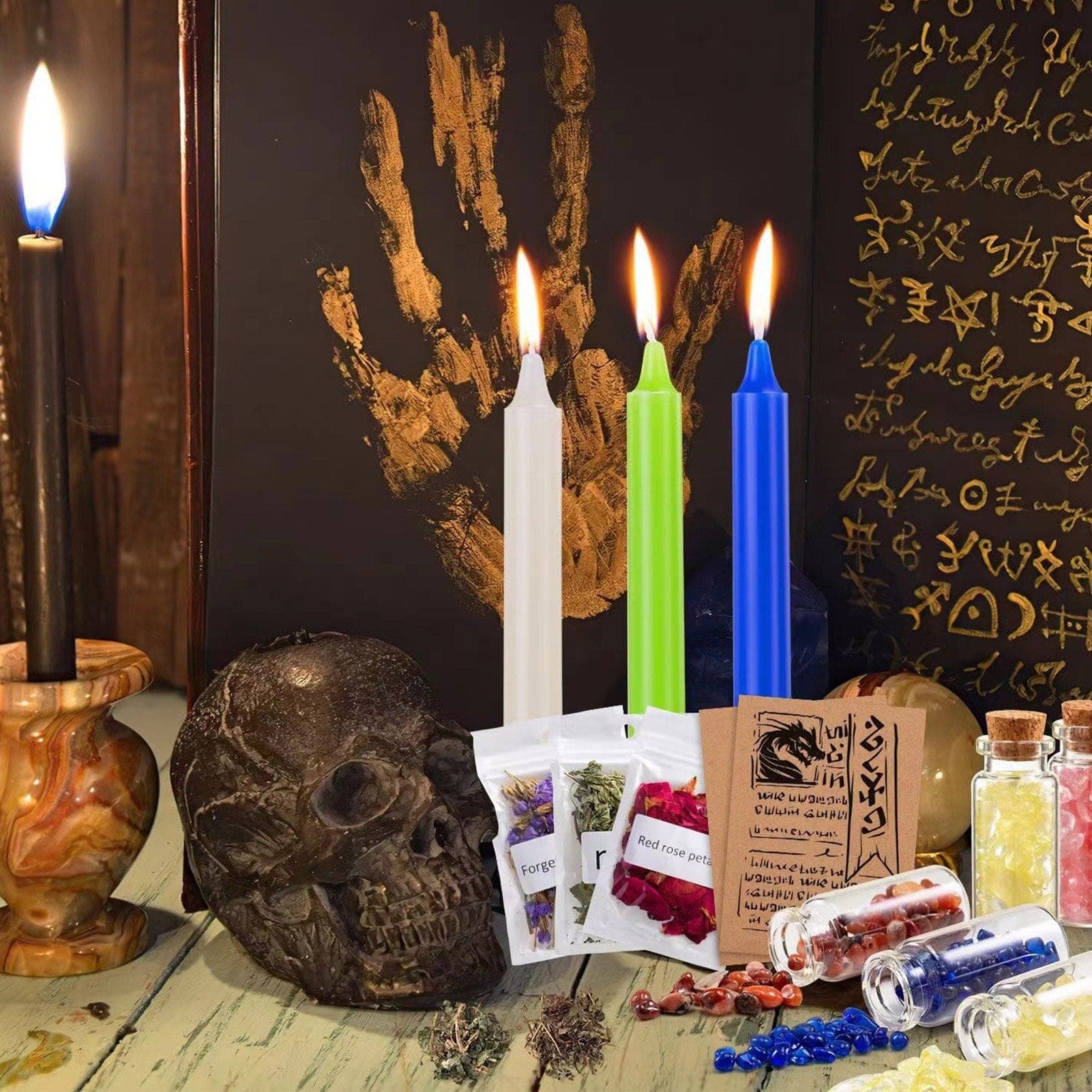 Wider view of white, green and blue ritual candles with a skull, book and other objects on a dark altar surface.