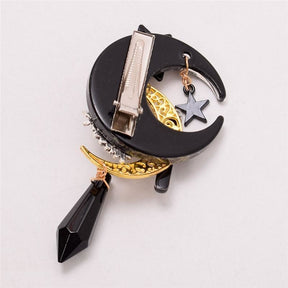 Back of the crescent moon hair accessory, showing its flat silver-tone hinged clip attached to the black crescent and dangling decorative charms below.