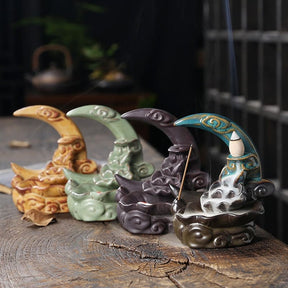 Four crescent moon incense burners grouped on a wooden slab, with Blue in front and Black, Green and Yellow behind it.