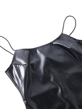 Close view of the glossy black dress's scoop neckline and slender shoulder straps.