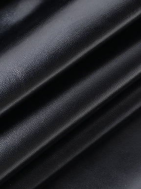 Glossy black dress fabric gathered into folds, showing its smooth surface and fine texture.