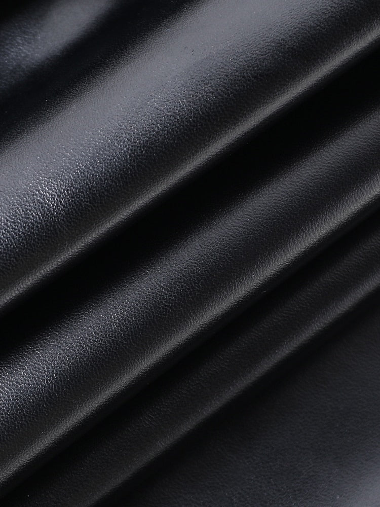 Glossy black dress fabric gathered into folds, showing its smooth surface and fine texture.