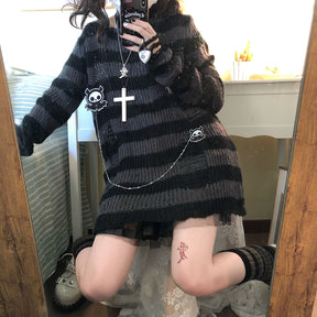 Grey and black long striped sweater in a closer mirror view, with a chain draped across the lower front and a black skirt peeking below the hem.