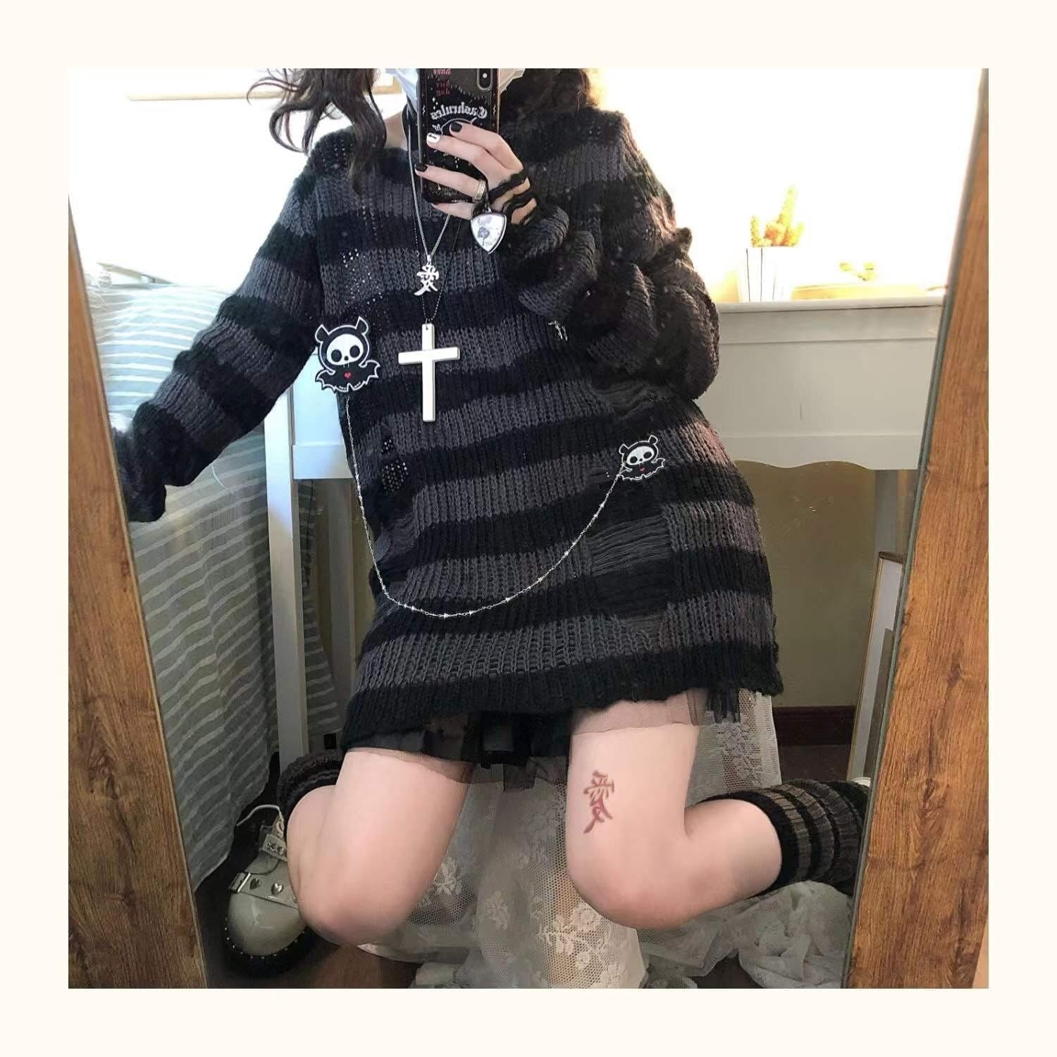 Fuller mirror view of a long grey and black striped sweater worn over a short black skirt, with one knee bent and a chain across the front.