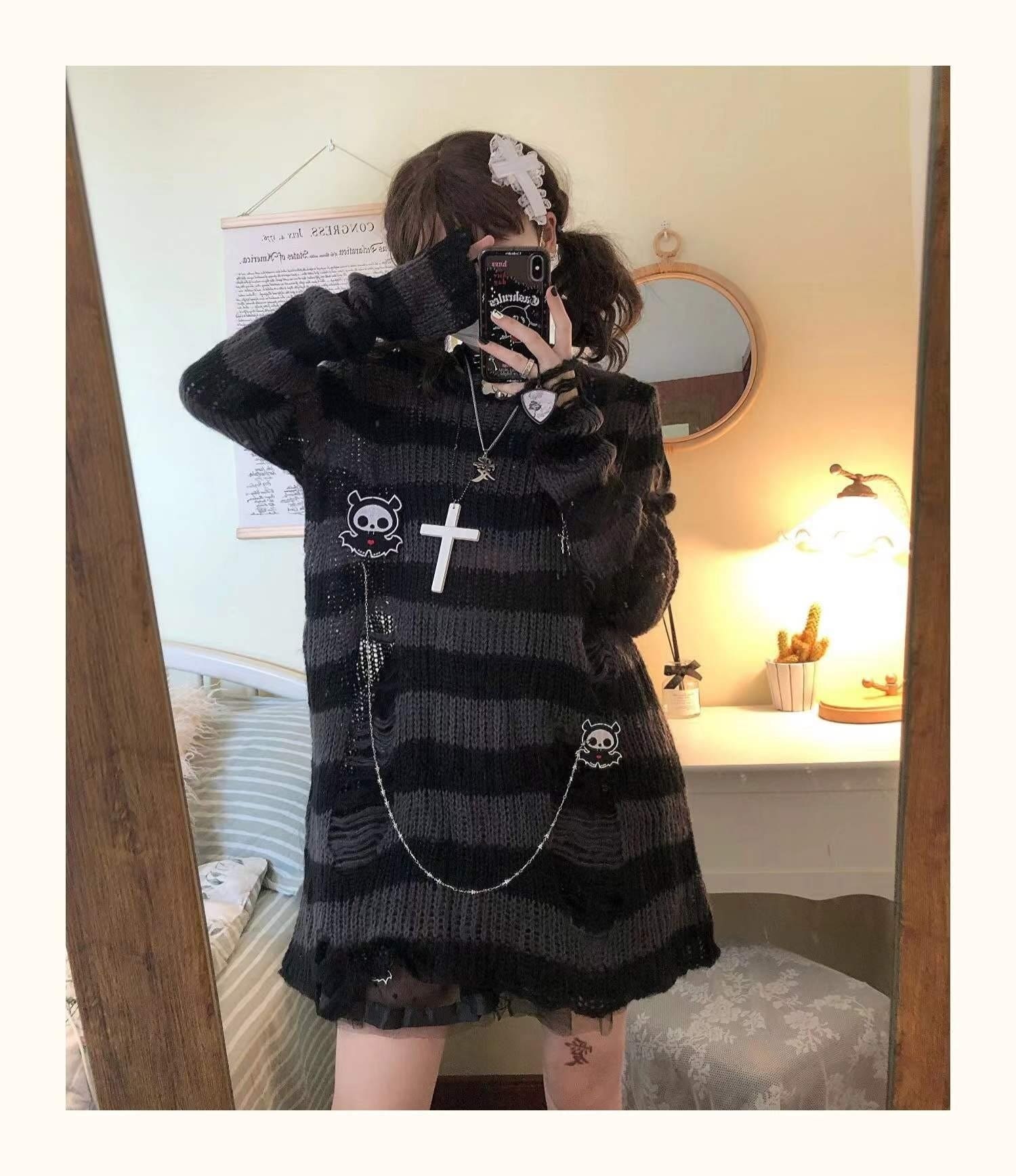 Grey and black long sweater in a full-length mirror pose with one arm lifted to the head. Long sleeves and the draped lower body are visible.