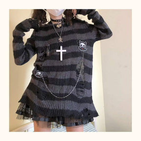 Front view of a grey and black long sweater with both arms raised, showing the wide sleeve shape and open distressed sections near the sides.