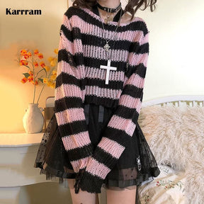 Pink and black cropped knit sweater worn with a separate black skirt in a bedroom. Long sleeves, a loose neckline and open knit texture are visible, with supplier text in the corner.