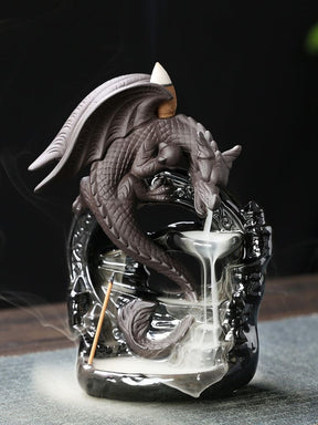 Gray dragon backflow incense burner breathing smoke into tiered bowls on a glossy black arch-shaped base, with mist pooling below its curled tail.
