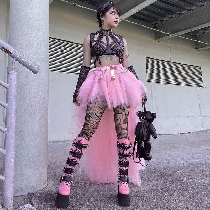 Pink high-low tutu skirt worn outdoors beside industrial railings, with a dark crop top and chunky knee-high boots.