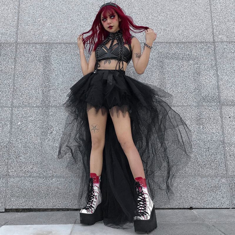 A red-haired model stands against a gray wall in the black high-low mesh skirt, with tall boots beneath its layered points.