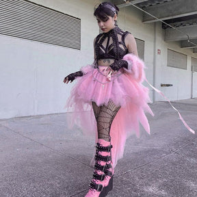 The pink fairy grunge skirt shown as a model turns beside a railing, with the loose mesh layers falling behind the legs.