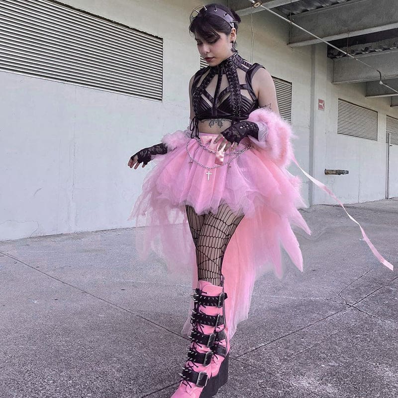 The pink fairy grunge skirt shown as a model turns beside a railing, with the loose mesh layers falling behind the legs.