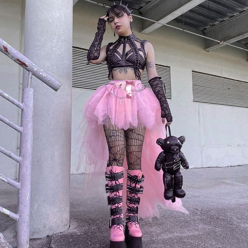 Pink mesh skirt worn with black arm warmers and a dark bear-shaped bag, with one hand raised near the model’s head.